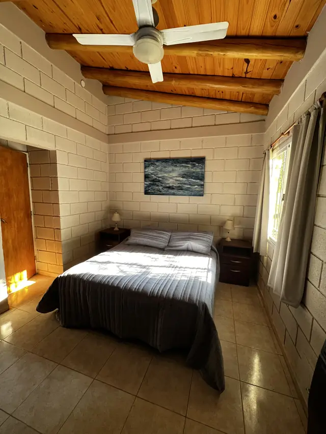 Dormitorio con techo de madera y ventilador