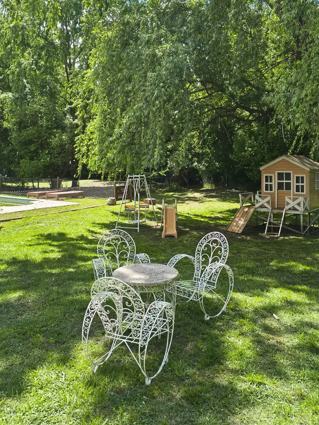 Jardín con juego de sillas de hierro y casita de juegos