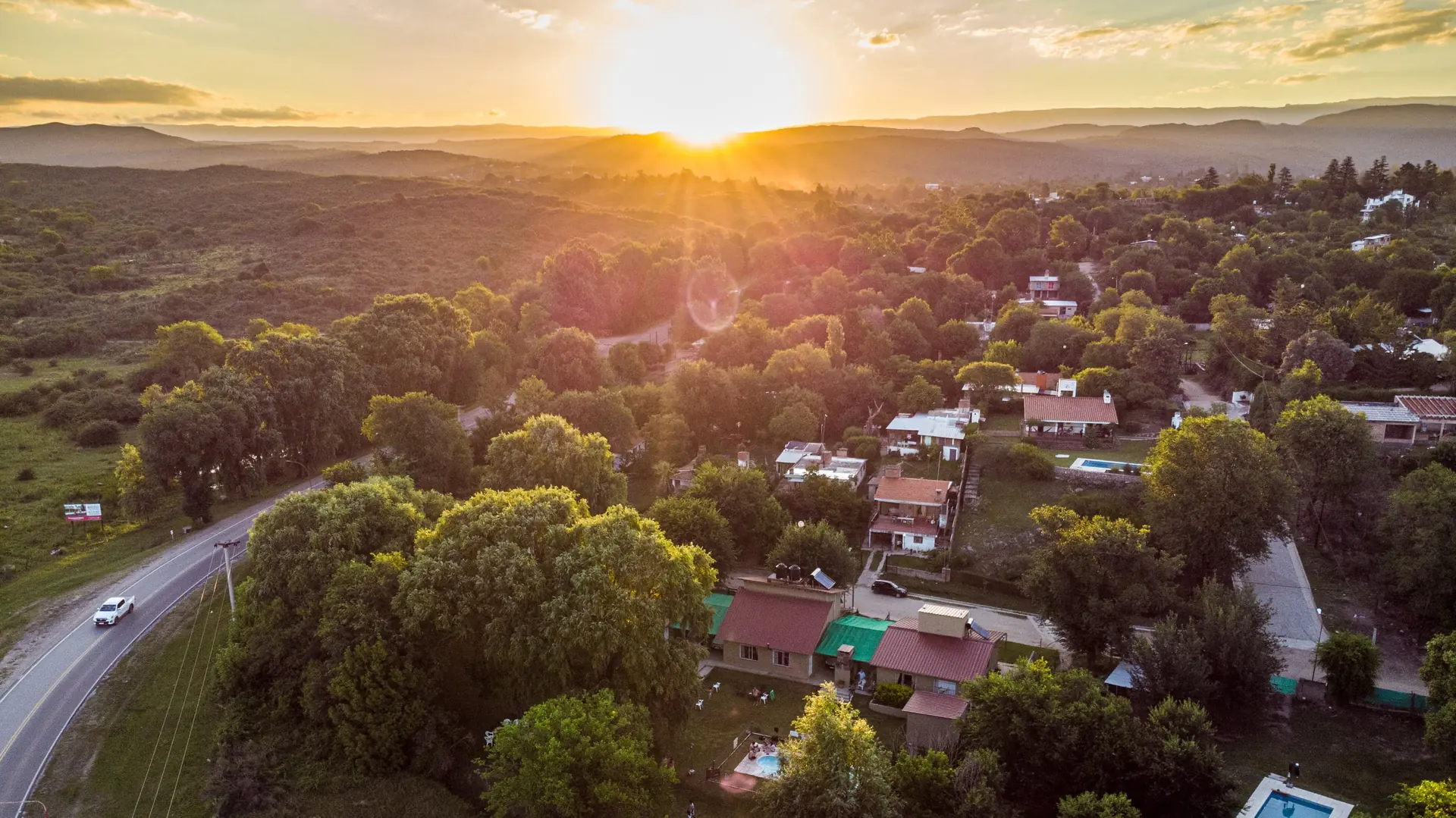 Vista aérea de las sierras al atardecer, con el pueblo y la arboleda